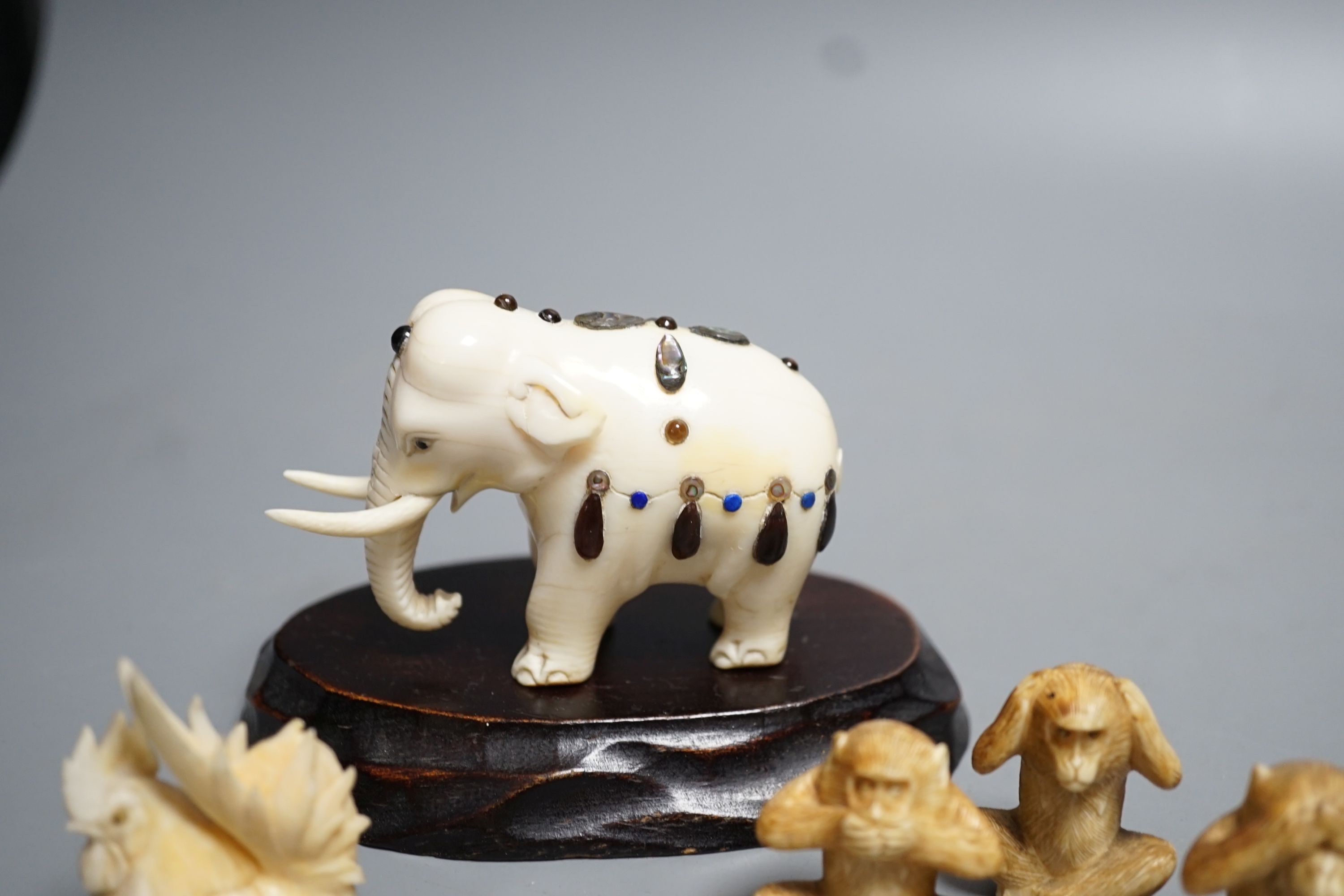 A Japanese Ivory and Shibayama style model of an elephant, three Japanese Ivory figures of the three wise monkeys and three Japanese ivory models of chickens and a chick, wood stand, all late 19th/early 20th century